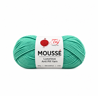 A skein of Teji Mousse Luxurious Anti Pill Yarn in a vibrant mint green color, featuring a white paper label with red and black branding, set against a plain white background.
