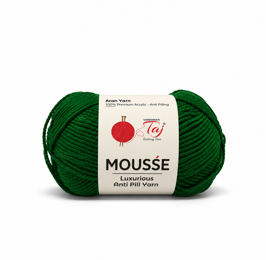 A single skein of dark green Mousse yarn with a white paper label, shown on a clean white background. The label features the brand 'Taj' and the product line 'Mousse'.