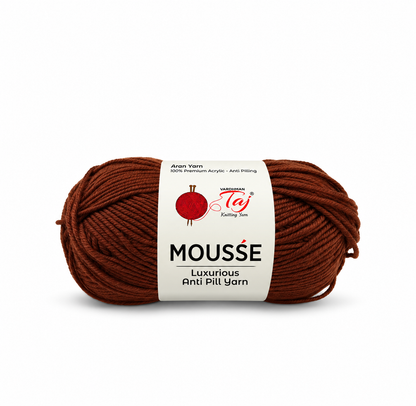 A skein of brown yarn with a white paper label that reads 'MOUSSE Luxury Anti Pili Yarn' and shows the 'Taj' brand logo, set against a plain white background.